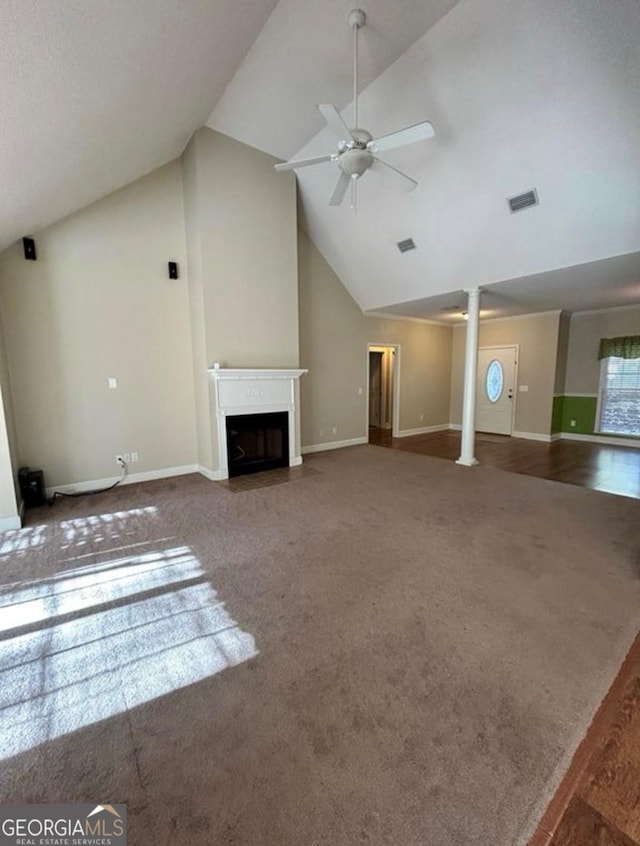 unfurnished living room with a fireplace with flush hearth, lofted ceiling, ornate columns, carpet flooring, and ceiling fan