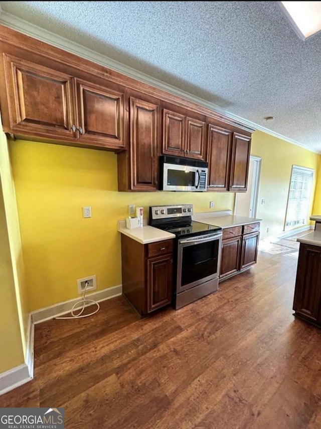 kitchen featuring dark wood-type flooring, light countertops, a textured ceiling, and appliances with stainless steel finishes