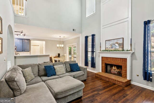 2267 Howell Farms Trl, Acworth, GA 30101 - living room with a high ceiling, an inviting chandelier, dark wood-type flooring, baseboards, and a brick fireplace