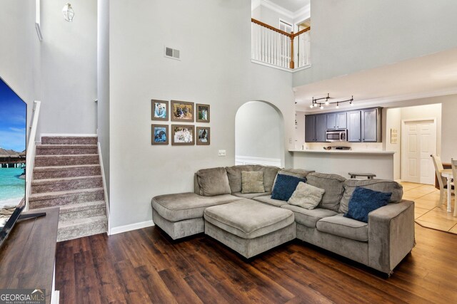 2267 Howell Farms Trl, Acworth, GA 30101 - living room with a towering ceiling, visible vents, ornamental molding, dark wood-type flooring, and baseboards