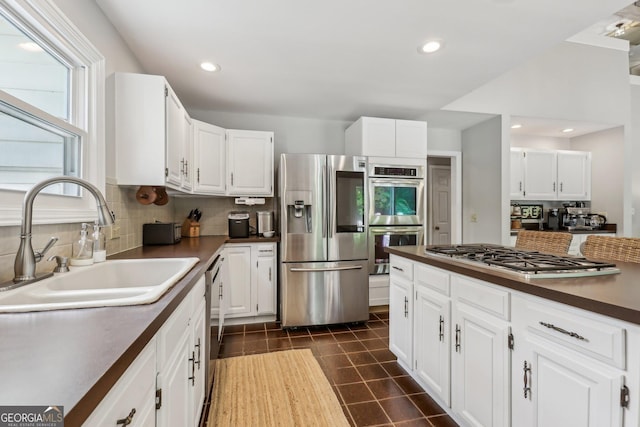 400 Peachtree Pkwy, Peachtree City, GA 30269 - kitchen featuring stainless steel appliances, a sink, dark countertops, decorative backsplash, and white cabinetry