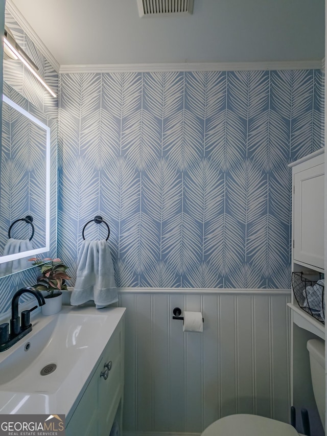 bathroom featuring wainscoting, toilet, visible vents, and wallpapered walls
