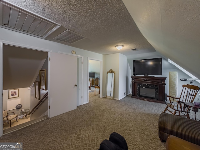 carpeted living room featuring a high end fireplace, vaulted ceiling, a textured ceiling, and visible vents