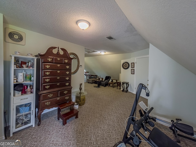 workout area featuring carpet, visible vents, and a textured ceiling
