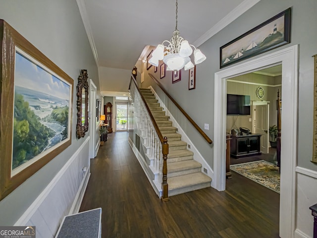stairway with wood finished floors, crown molding, and an inviting chandelier