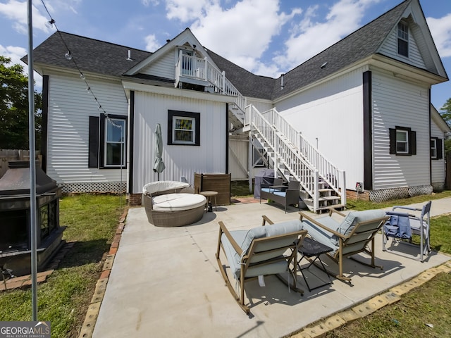 rear view of house with a shingled roof, a patio, and stairway