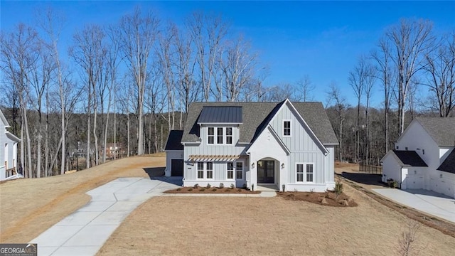 view of front of property with board and batten siding, a standing seam roof, a shingled roof, and concrete driveway