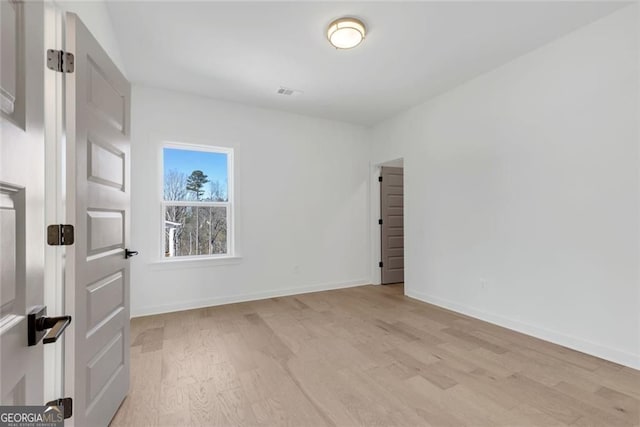 unfurnished room featuring light wood-style flooring, visible vents, and baseboards