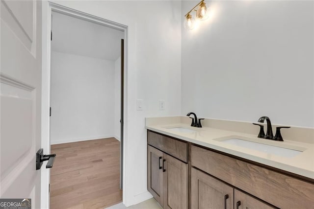 bathroom with double vanity, wood finished floors, and a sink