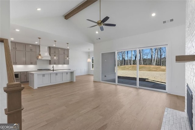 unfurnished living room featuring visible vents, a ceiling fan, light wood-type flooring, beam ceiling, and a fireplace