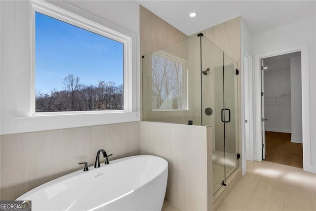full bath featuring a soaking tub, a wealth of natural light, and a stall shower