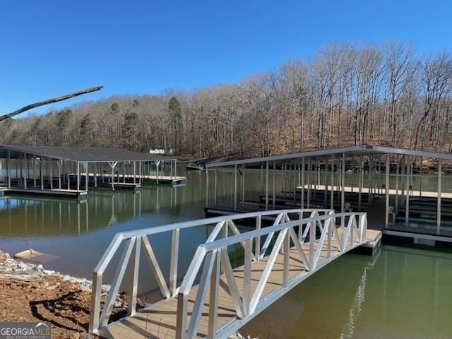 view of dock with a forest view and a water view
