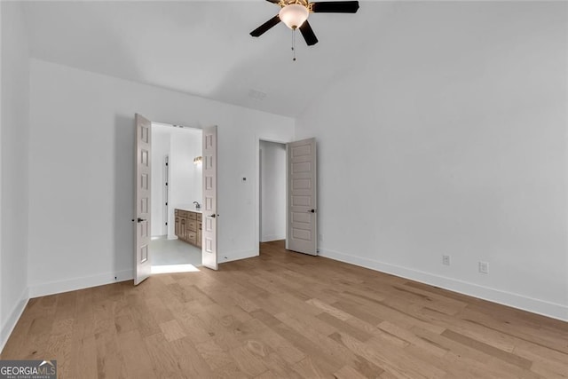 unfurnished bedroom featuring ensuite bathroom, light wood-style flooring, baseboards, lofted ceiling, and visible vents