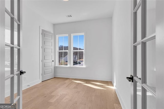 unfurnished bedroom with visible vents, french doors, wood finished floors, and baseboards