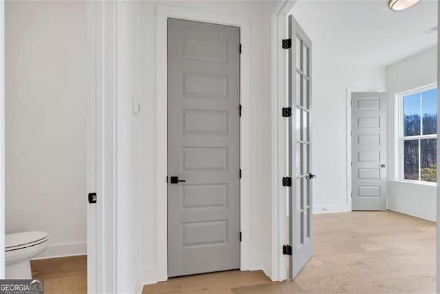corridor with light wood-type flooring and baseboards