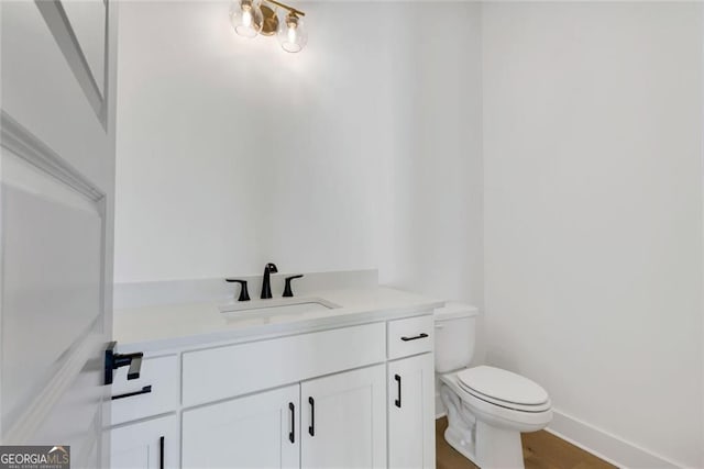 bathroom featuring baseboards, wood finished floors, vanity, and toilet