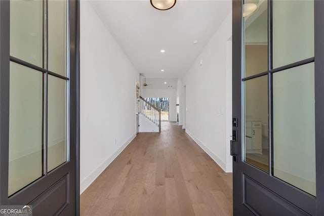 hall featuring recessed lighting, baseboards, stairway, and light wood-style flooring