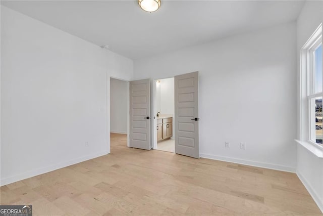 unfurnished bedroom with baseboards, light wood-style floors, and multiple windows
