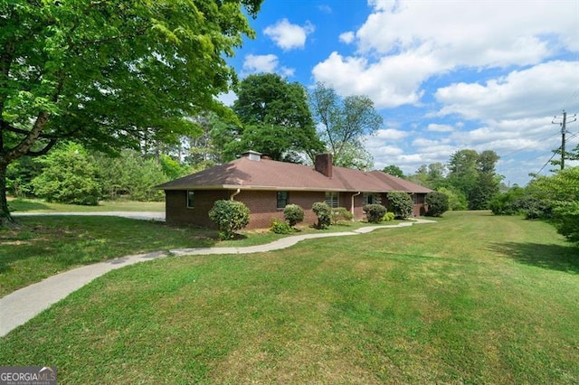 ranch-style home with a chimney, brick siding, and a front lawn
