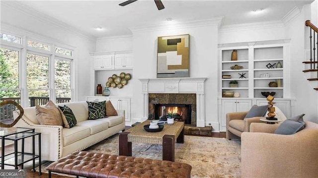 living room with ceiling fan, wood finished floors, ornamental molding, a fireplace, and built in features