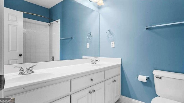 full bathroom featuring toilet, double vanity, baseboards, and a shower