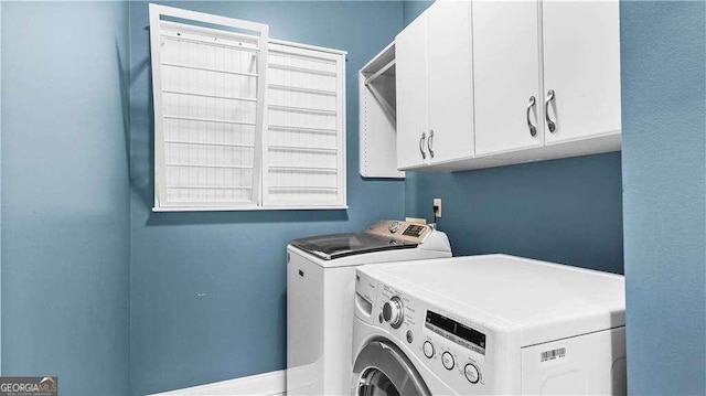 washroom with washing machine and clothes dryer and cabinet space