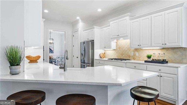 kitchen featuring stainless steel fridge, a kitchen bar, white cabinets, a peninsula, and crown molding