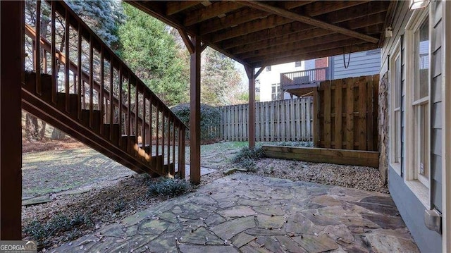view of patio featuring fence and stairway