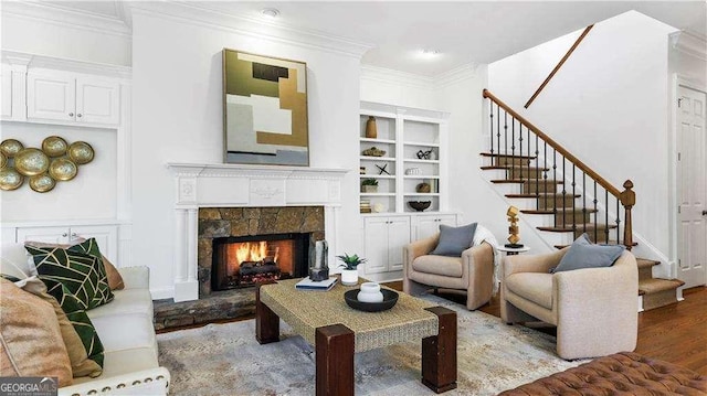 living room featuring crown molding, wood finished floors, stairs, a fireplace, and built in features