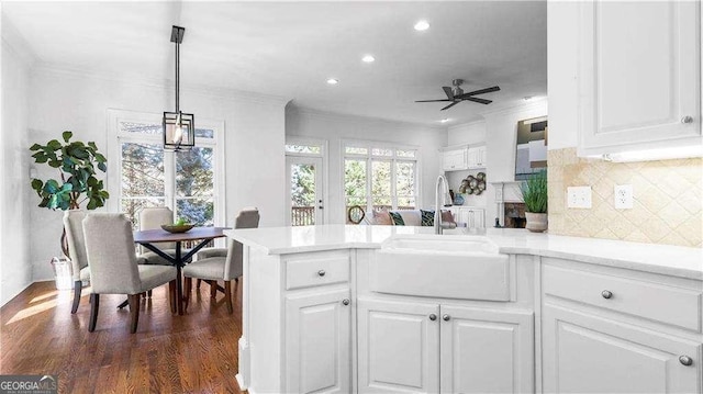 kitchen featuring a peninsula, ceiling fan, a sink, white cabinets, and light countertops
