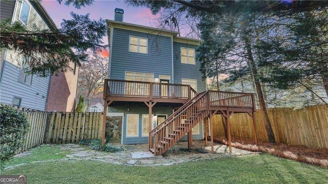 back of property at dusk with a deck, stairs, and a chimney