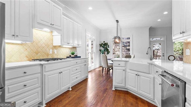 kitchen featuring appliances with stainless steel finishes, a sink, ornamental molding, white cabinetry, and light countertops