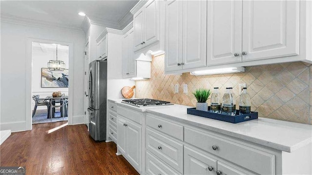 kitchen with appliances with stainless steel finishes, white cabinets, light countertops, and crown molding