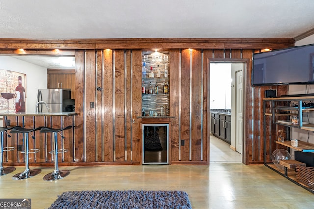 kitchen with stainless steel microwave, black / electric stove, a kitchen breakfast bar, and light wood-type flooring