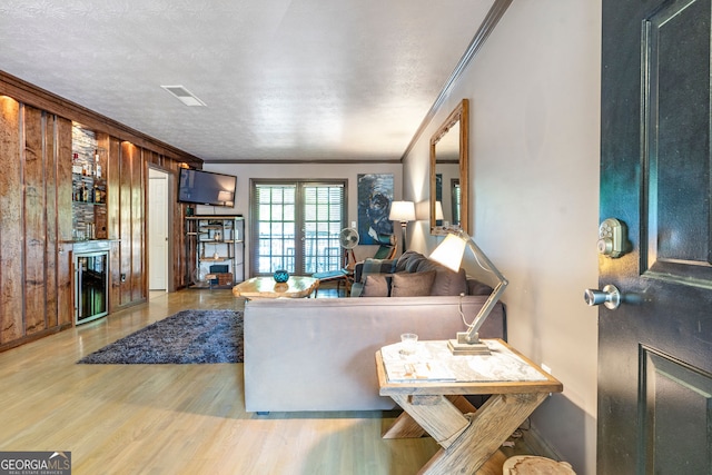 living room featuring ornamental molding, wood finished floors, baseboards, and a textured ceiling