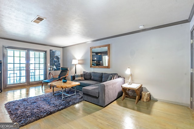 living room featuring ornamental molding, baseboards, wood finished floors, and a textured ceiling