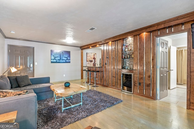 living area with bar area, ornamental molding, wood finished floors, and baseboards
