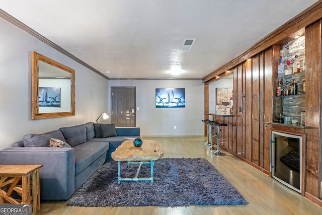 living room with beverage cooler, light wood-type flooring, and bar