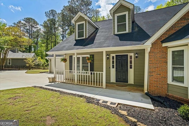 view of front of home featuring a front lawn, driveway, a porch, fence, and a garage