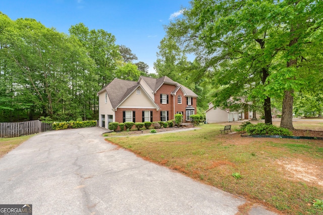10044 Point View Dr, Jonesboro, GA 30238 - colonial house featuring fence, an attached garage, a front lawn, brick siding, and driveway