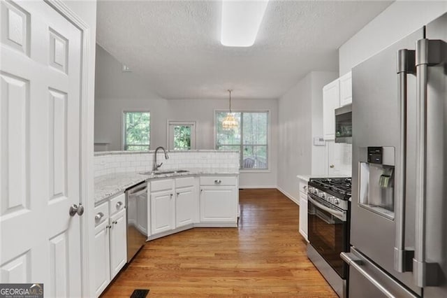 kitchen featuring white cabinets, light wood-style floors, a textured ceiling, and appliances with stainless steel finishes