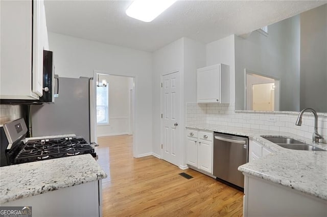 kitchen featuring light wood-style flooring, tasteful backsplash, stainless steel appliances, and a sink