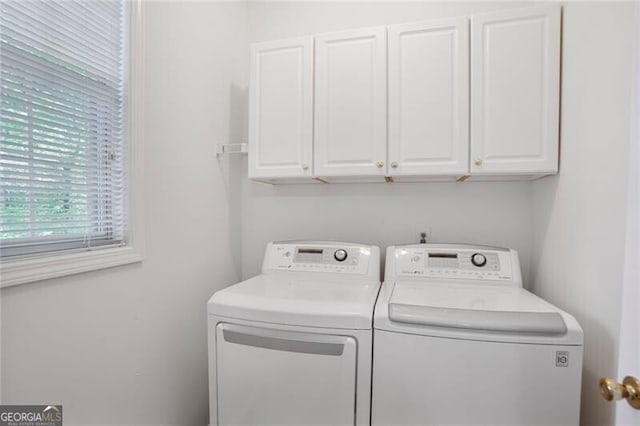 clothes washing area featuring washing machine and dryer and cabinet space