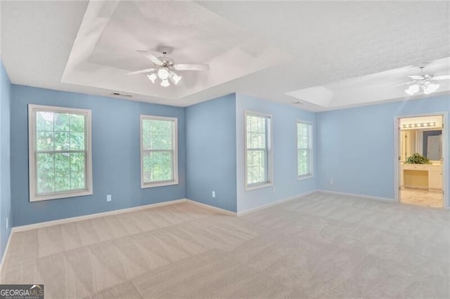 unfurnished bedroom featuring light colored carpet, baseboards, a ceiling fan, and a raised ceiling
