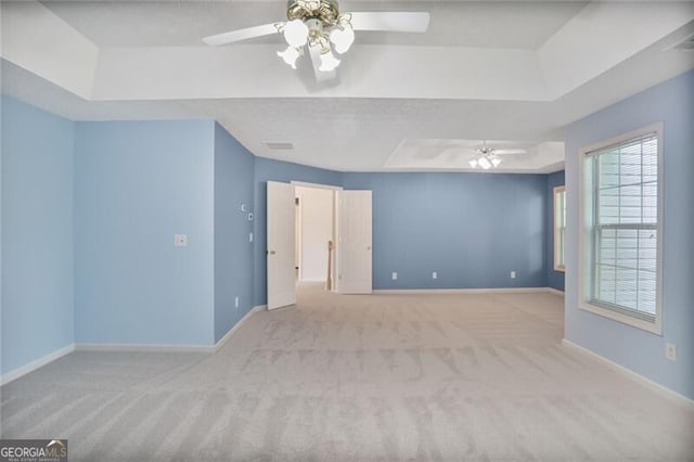 unfurnished room with ceiling fan, carpet flooring, and a raised ceiling