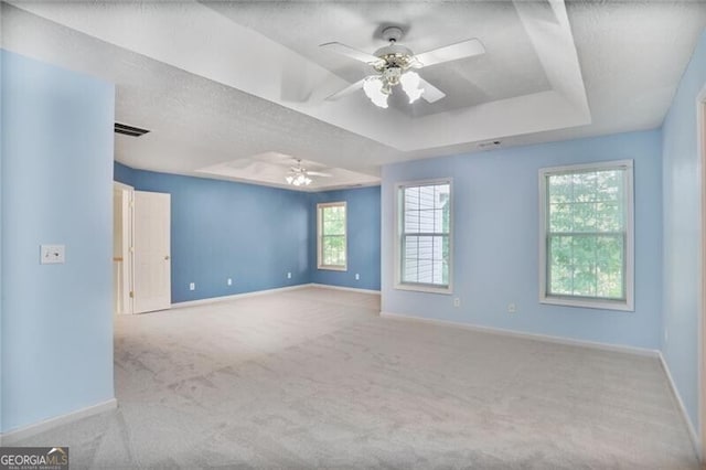 empty room featuring baseboards, carpet flooring, a raised ceiling, and ceiling fan