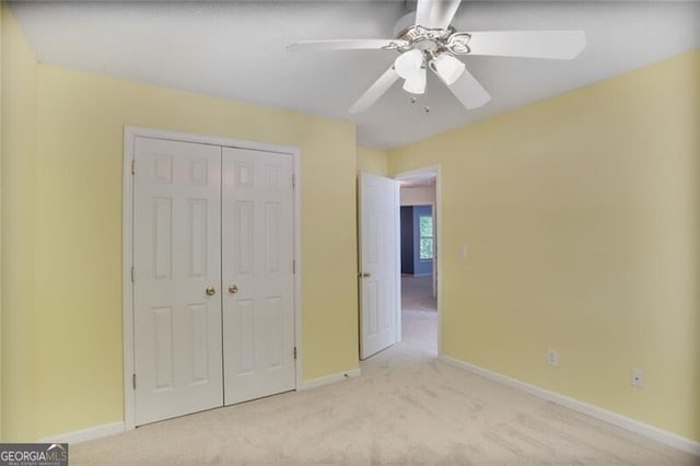 unfurnished bedroom with light colored carpet, ceiling fan, baseboards, and a closet