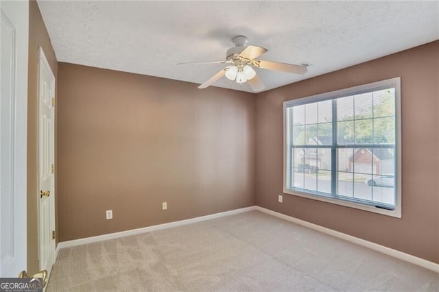 unfurnished room with ceiling fan, a textured ceiling, baseboards, and light carpet