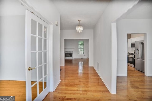 corridor with a notable chandelier and light wood-style floors