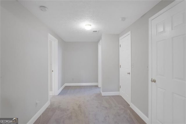 interior space with visible vents, baseboards, carpet, and a textured ceiling
